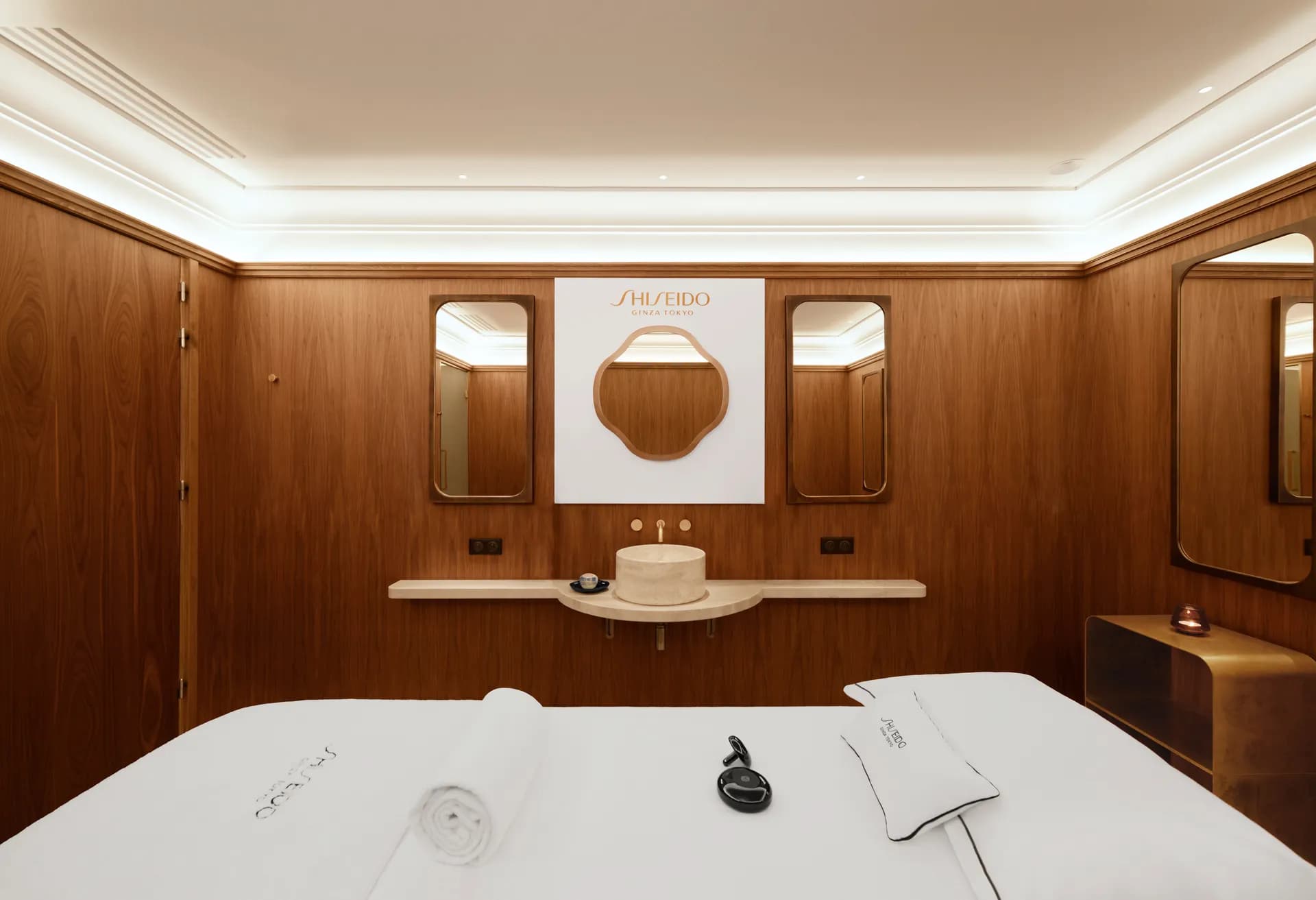 Cabine de soin d'un spa d'hôtel de luxe, aux murs en boiseries, avec table de massage et produits Shiseido